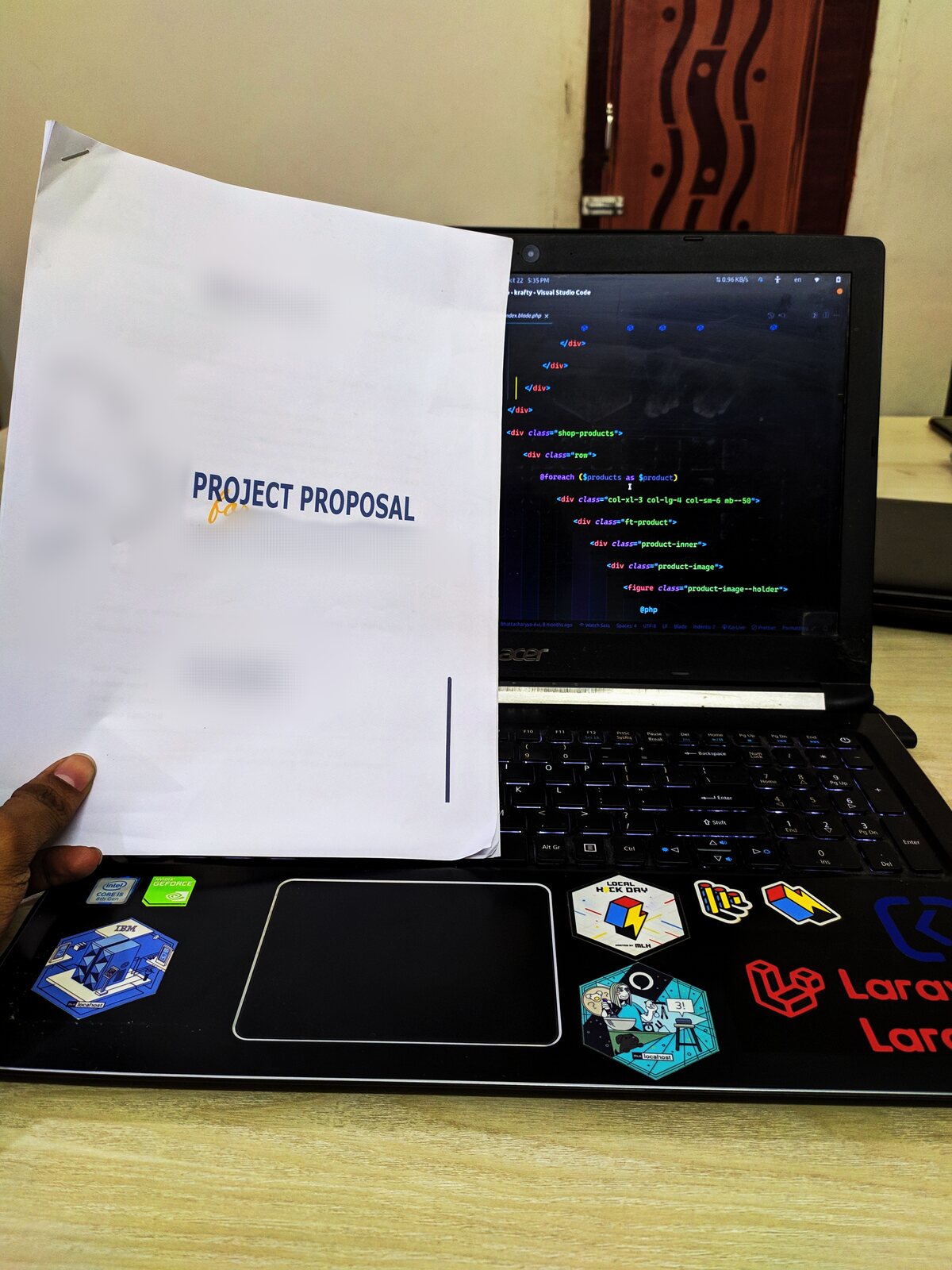 A clear water bottle standing beside a laptop showing code.