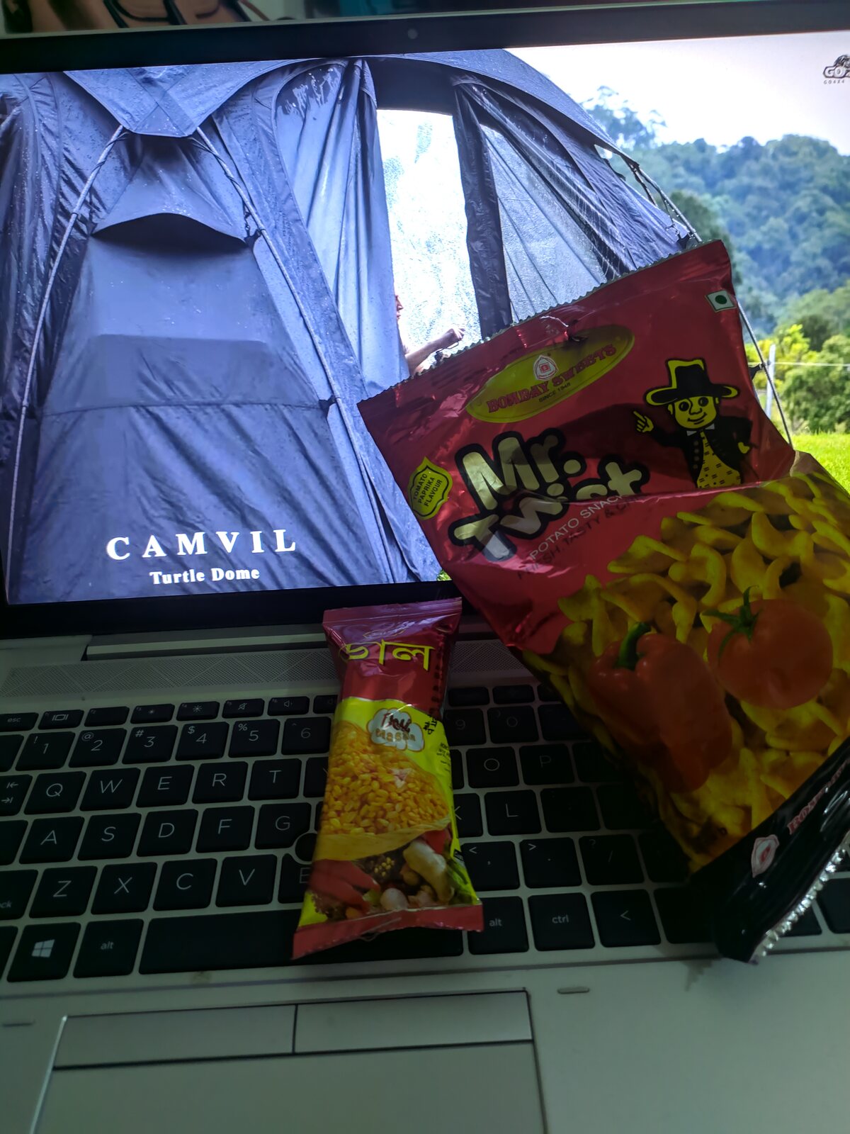 A laptop playing a camping video next to a plate of food.