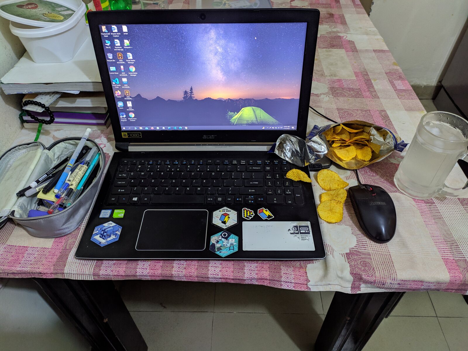 A bowl of cereal and a water bottle in front of a laptop.