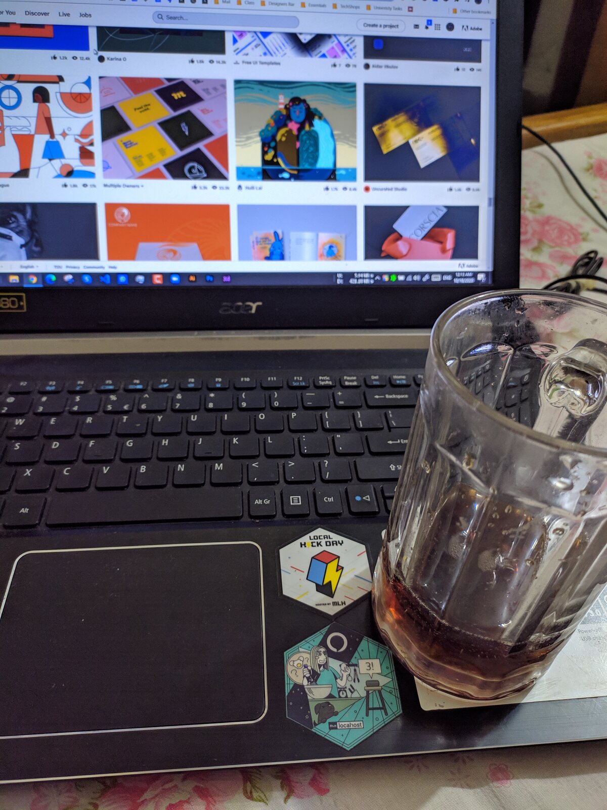A laptop and a glass of tea on a desk late at night.