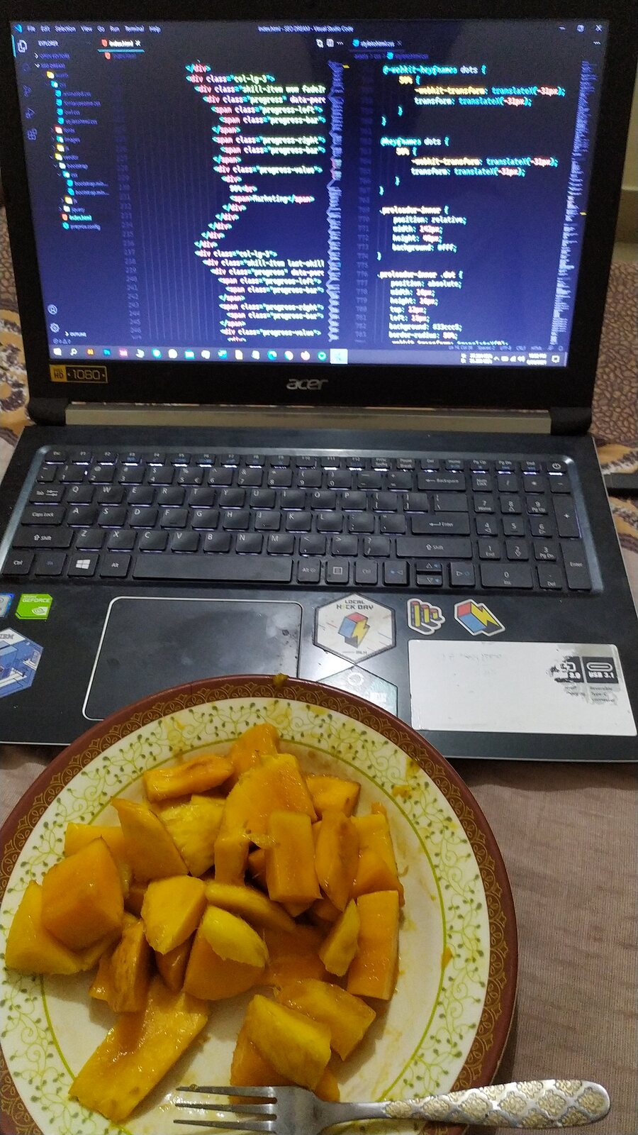 A plate of sliced mango next to a laptop showing code.