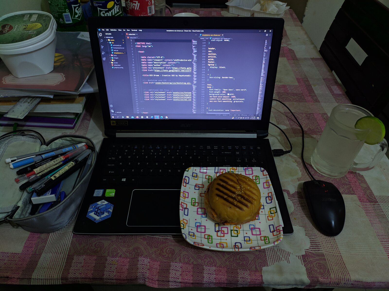 A laptop with a night-sky wallpaper on a dining table beside a plate of mango.