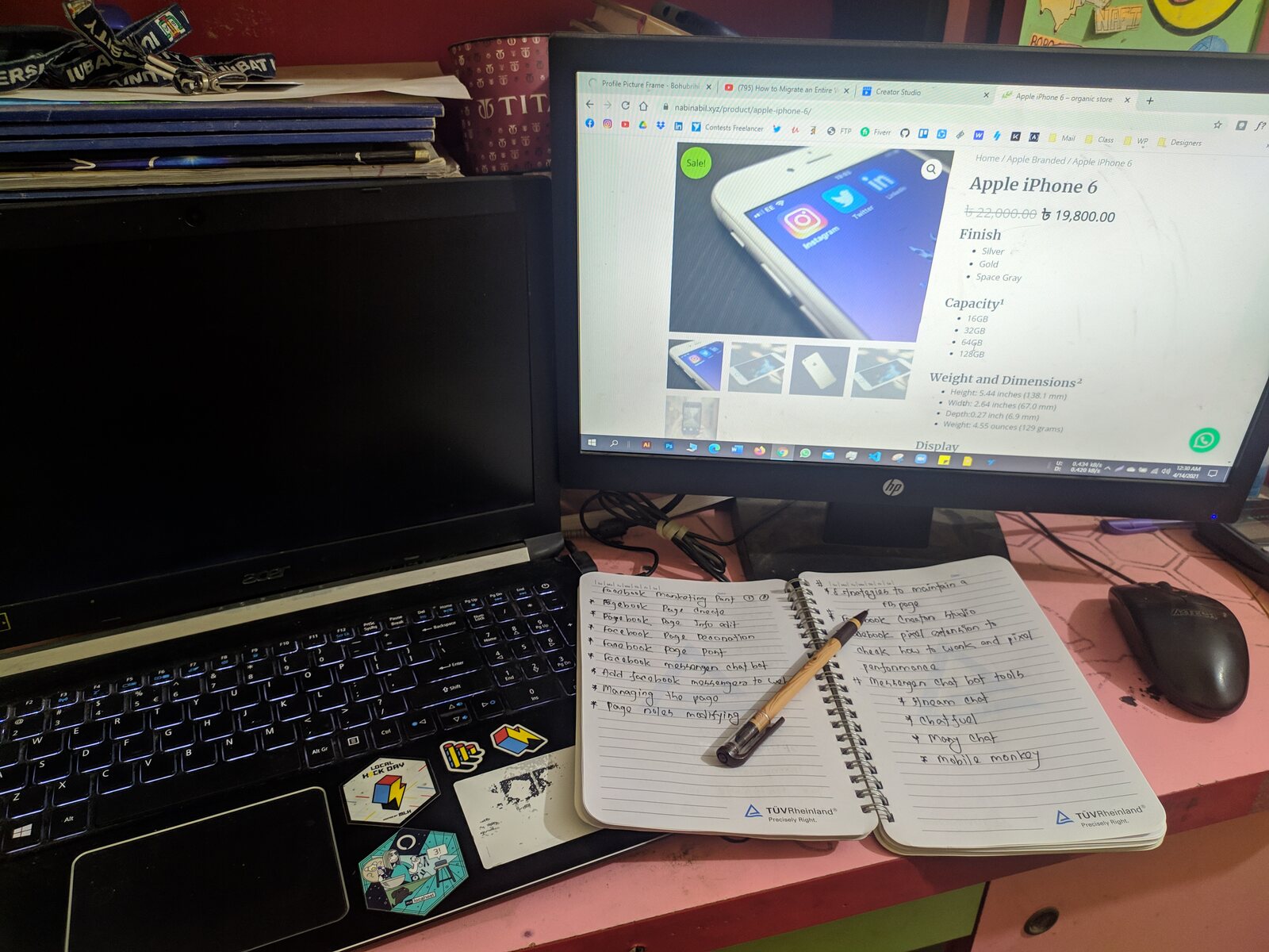 An open notebook and pen in front of a laptop showing code.