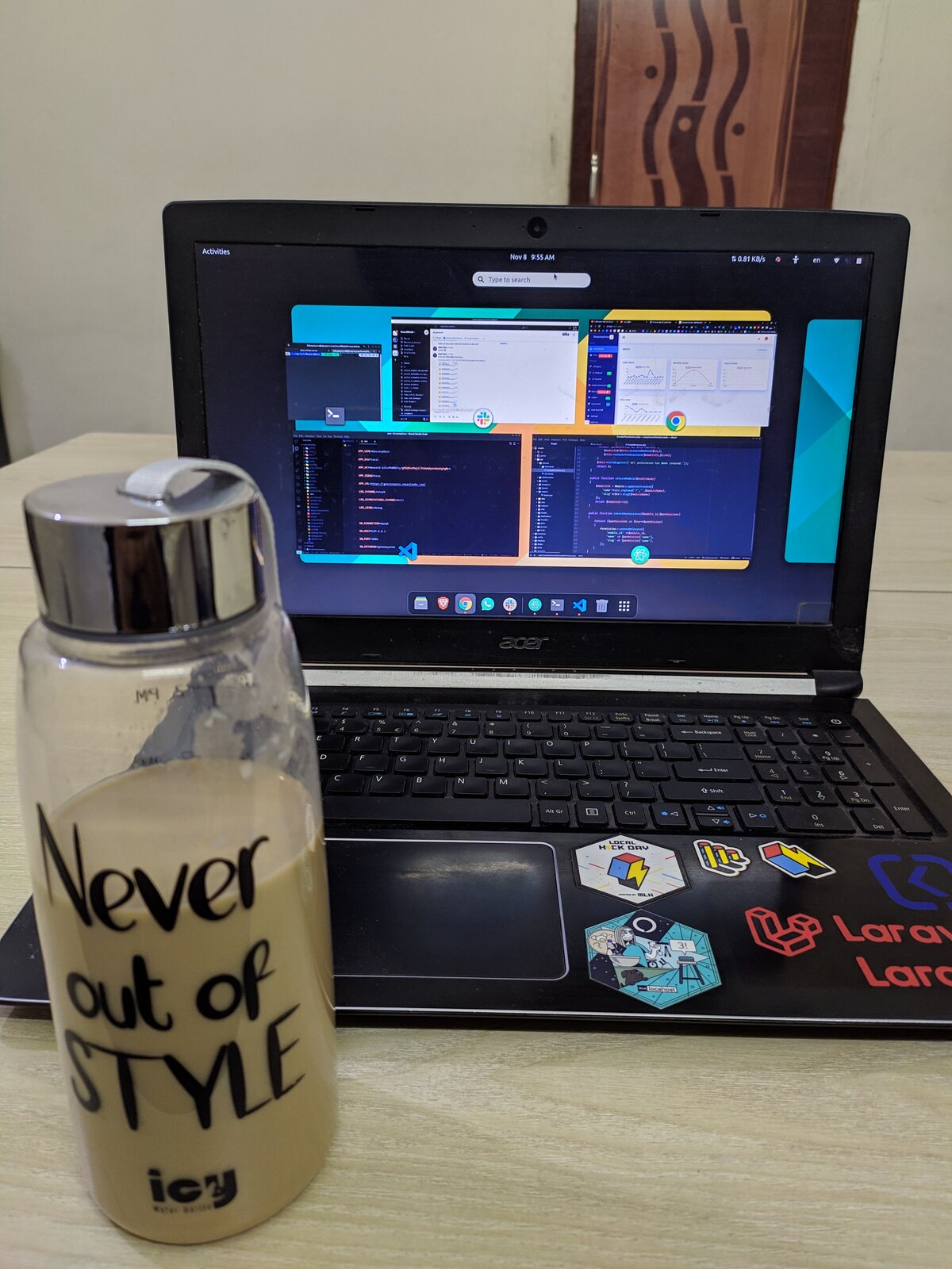 A coffee cup and notebook beside a monitor at an office desk.