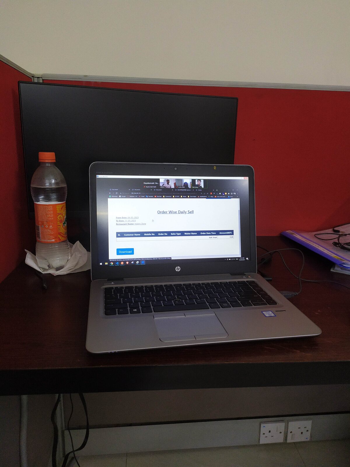 A tea cup and notebook on a wide office desk with a monitor.
