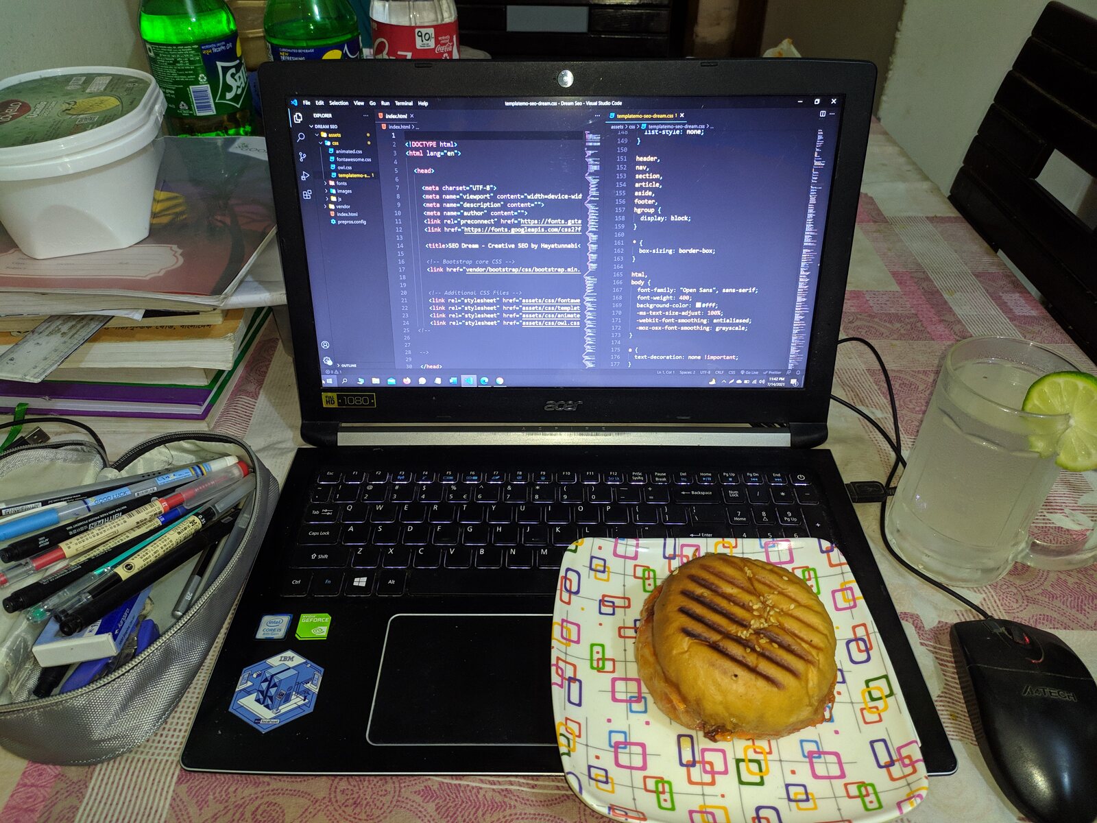 A plate with paratha next to a laptop showing code.