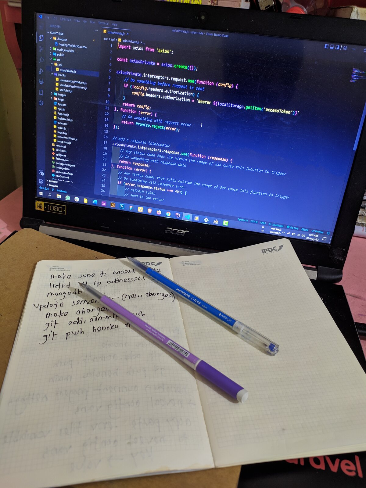 A notebook with diagrams beside a laptop showing code, late at night.