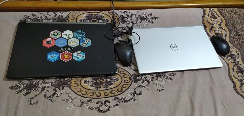 A closed laptop covered in stickers beside a mouse on a patterned mat.