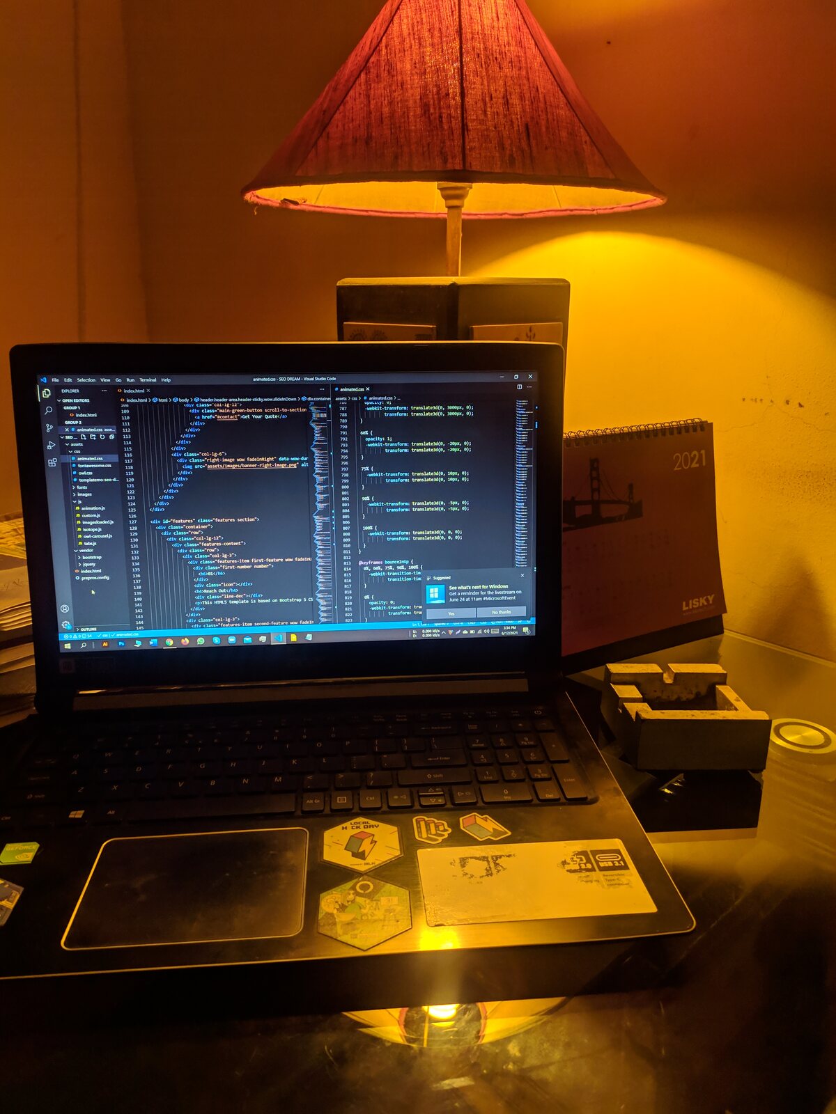 A laptop showing code under the warm glow of a desk lamp.
